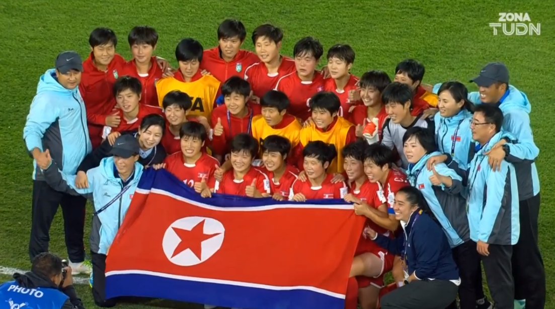 DPRK team posing for a photo with the flag